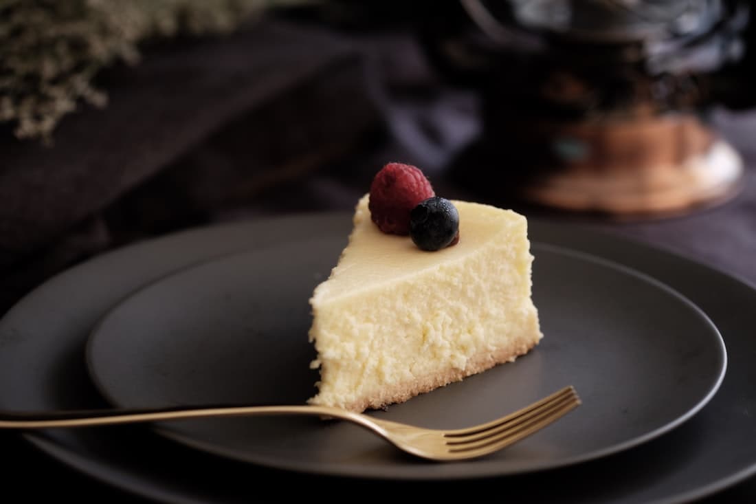 Üzerinde frambuaz ve yaban mersini olan New York cheesecake dilimi